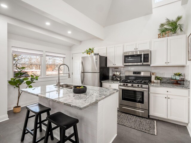 kitchen featuring white cabinetry, stainless steel appliances, and an island with sink