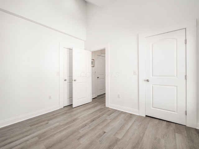 unfurnished bedroom with a high ceiling and light wood-type flooring