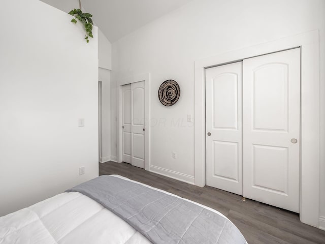 bedroom featuring two closets, wood-type flooring, and vaulted ceiling