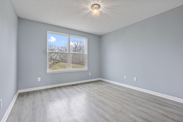 unfurnished room featuring light hardwood / wood-style floors and a textured ceiling