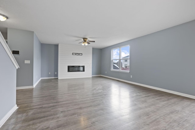 unfurnished living room featuring dark wood-type flooring, ceiling fan, and a fireplace