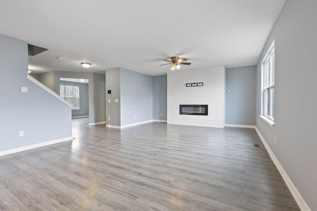 unfurnished living room featuring hardwood / wood-style flooring, a large fireplace, and ceiling fan