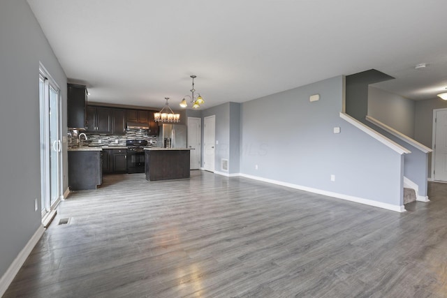 unfurnished living room with wood-type flooring, sink, and a notable chandelier