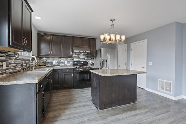 kitchen featuring range hood, sink, hanging light fixtures, a center island, and black appliances