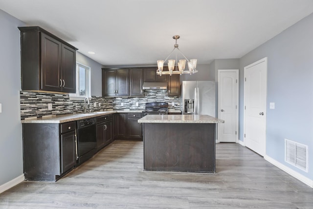 kitchen featuring sink, ventilation hood, hanging light fixtures, a kitchen island, and black appliances