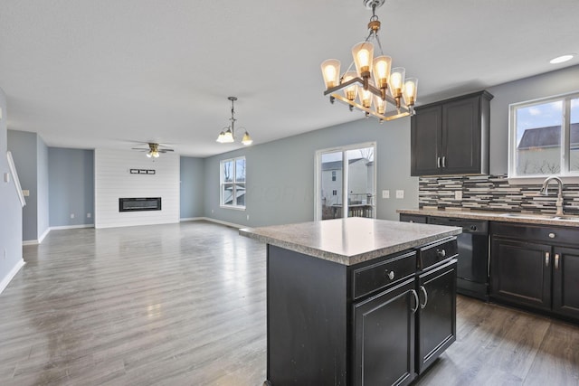 kitchen featuring pendant lighting, sink, a center island, black dishwasher, and a fireplace