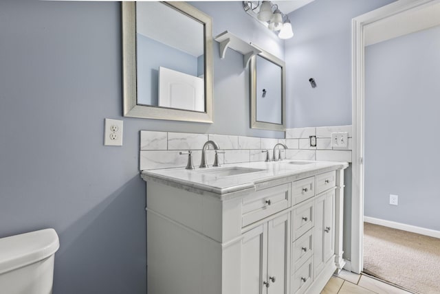 bathroom featuring vanity, toilet, and backsplash