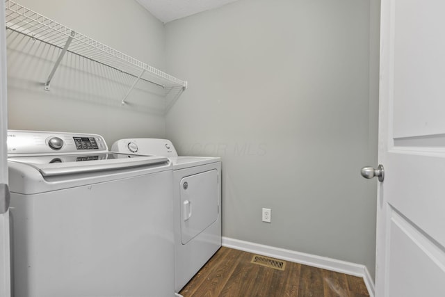 laundry area with dark hardwood / wood-style floors and washer and dryer