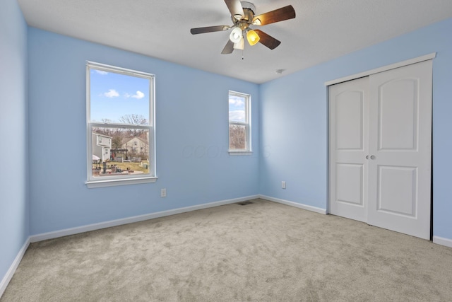 unfurnished bedroom with light carpet, ceiling fan, and a closet