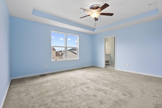 carpeted spare room featuring ceiling fan and a raised ceiling