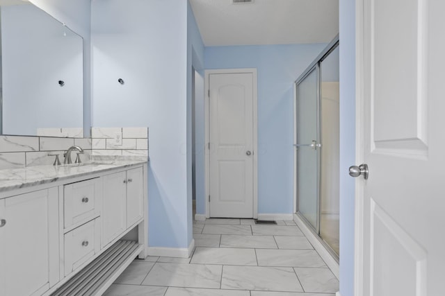 bathroom featuring vanity, decorative backsplash, and a shower with shower door