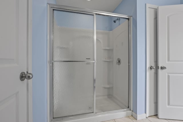 bathroom with a shower with shower door and tile patterned flooring