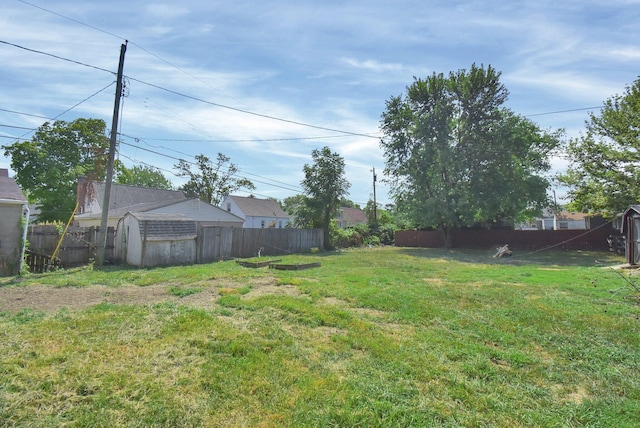 view of yard with an outbuilding, a fenced backyard, and a shed