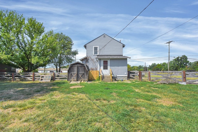 back of property with entry steps, a lawn, a fenced backyard, and a shed