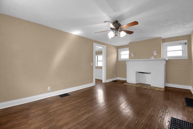 unfurnished living room featuring a fireplace, visible vents, wood finished floors, and baseboards