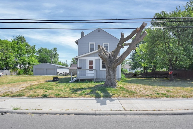 view of front of home featuring a garage, an outbuilding, a front lawn, and fence