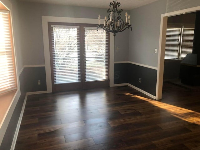 unfurnished dining area with dark hardwood / wood-style flooring and a chandelier