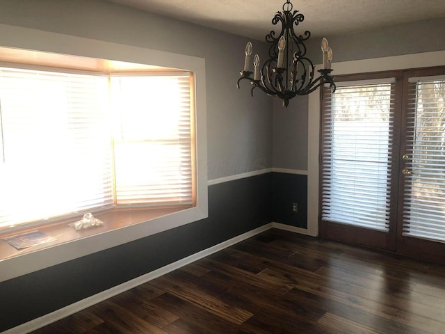 unfurnished room with dark hardwood / wood-style floors and an inviting chandelier