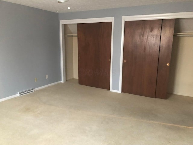 unfurnished bedroom featuring carpet and two closets