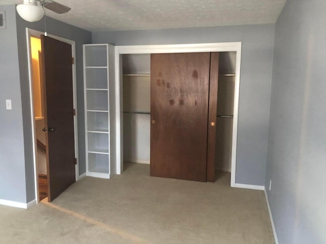 unfurnished bedroom featuring light carpet, a closet, and a textured ceiling