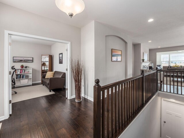 hallway featuring baseboards, an upstairs landing, hardwood / wood-style flooring, and recessed lighting