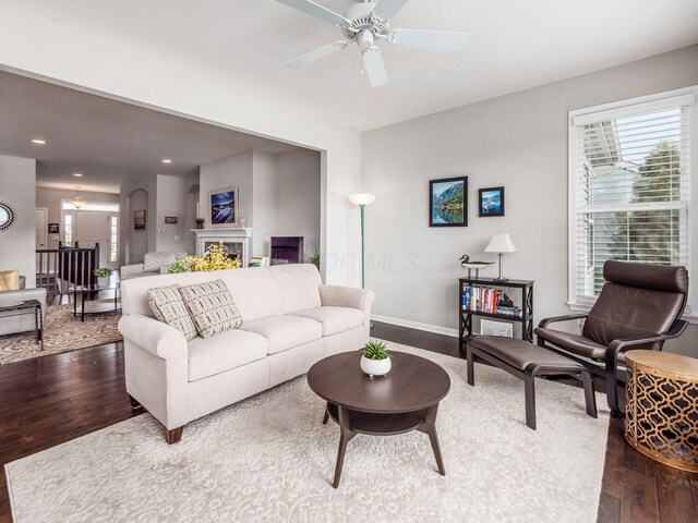 living room with a fireplace, recessed lighting, wood-type flooring, ceiling fan, and baseboards