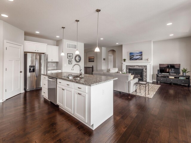 kitchen featuring stainless steel appliances, dark stone counters, a sink, visible vents, and dark wood-style floors