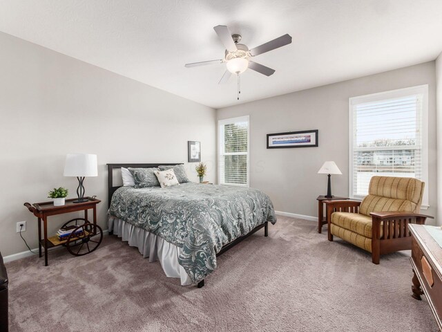 carpeted bedroom featuring a ceiling fan, multiple windows, and baseboards