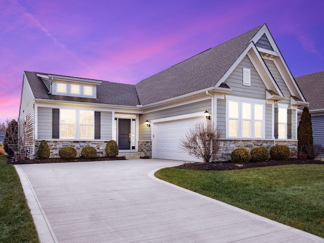 craftsman-style home featuring a shingled roof, concrete driveway, a lawn, an attached garage, and stone siding