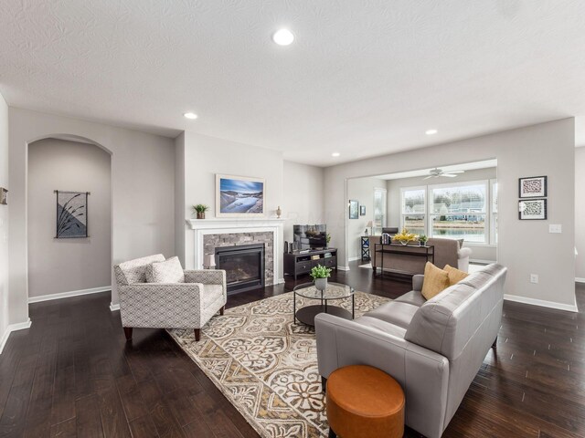 living area with recessed lighting, wood-type flooring, baseboards, and a glass covered fireplace