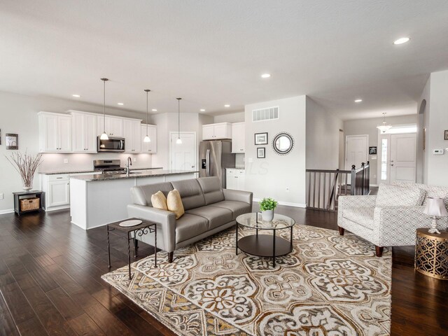 living room with arched walkways, recessed lighting, visible vents, baseboards, and dark wood finished floors