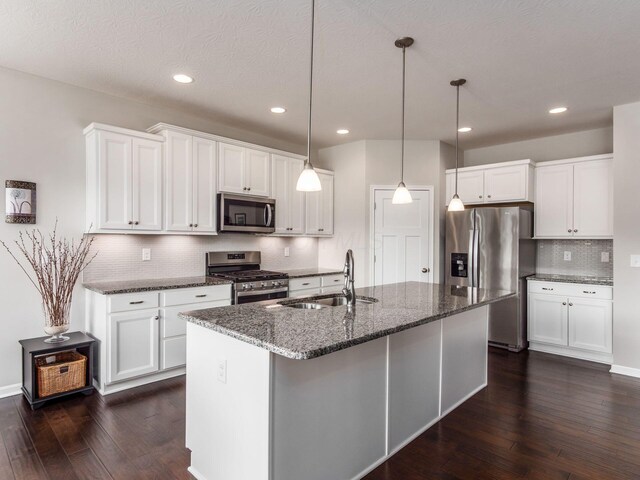 kitchen featuring dark wood-style floors, dark stone countertops, stainless steel appliances, and a sink