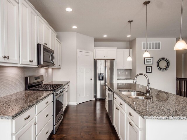 kitchen with dark wood-style floors, visible vents, appliances with stainless steel finishes, a sink, and an island with sink