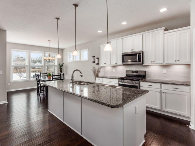 kitchen with plenty of natural light, dark wood-style floors, a sink, stainless steel appliances, and backsplash