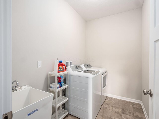 washroom featuring washer and dryer, laundry area, a sink, and baseboards