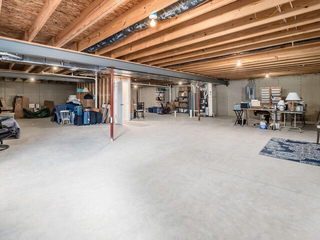 unfinished basement featuring electric panel and water heater