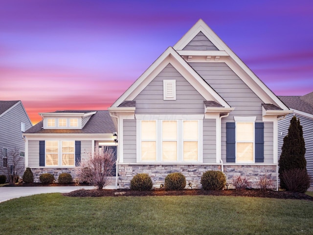 craftsman-style house with stone siding and a front yard