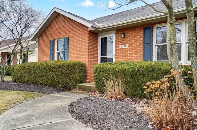 entrance to property with brick siding and roof with shingles