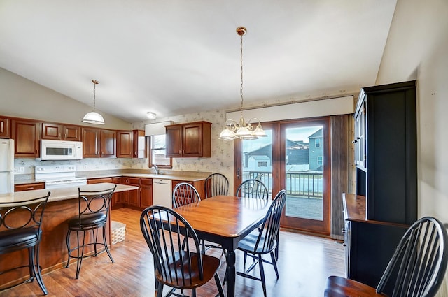 dining space featuring light wood-style floors, vaulted ceiling, and an inviting chandelier