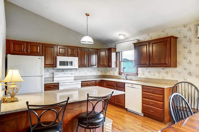 kitchen with lofted ceiling, hanging light fixtures, light wood-style flooring, white appliances, and wallpapered walls