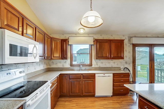 kitchen featuring wallpapered walls, white appliances, brown cabinetry, decorative light fixtures, and a sink