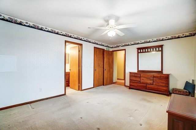 unfurnished bedroom featuring light carpet, connected bathroom, a ceiling fan, and baseboards