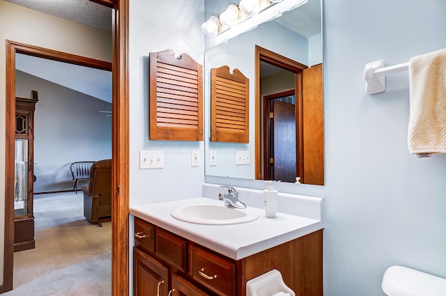 ensuite bathroom with toilet, vanity, ensuite bath, and a textured ceiling