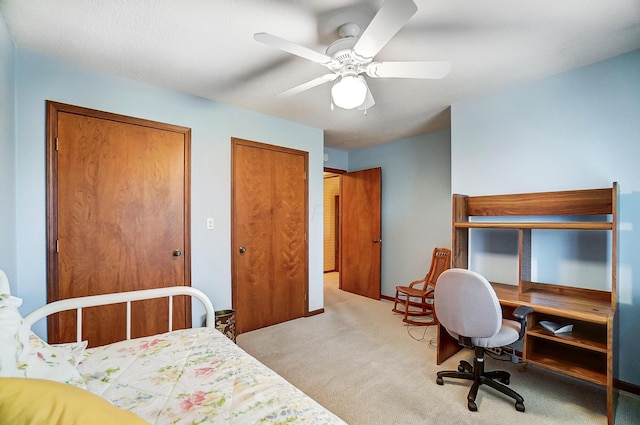 bedroom with ceiling fan, multiple closets, and light colored carpet