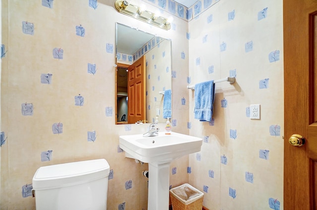 half bath with toilet and wallpapered walls