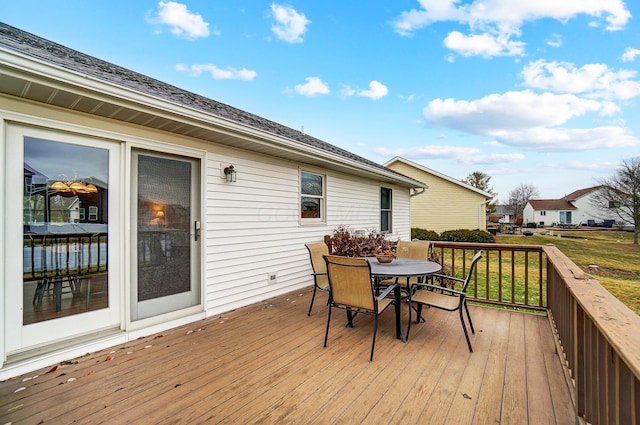 wooden deck with outdoor dining area and a yard