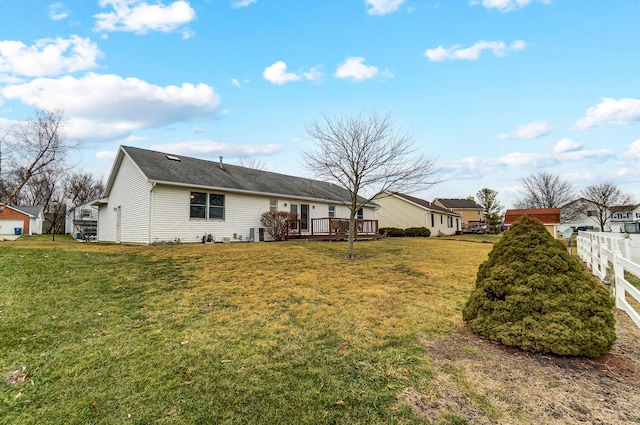 back of property featuring a residential view, fence, a deck, and a lawn