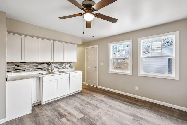 kitchen featuring tasteful backsplash, sink, white cabinets, ceiling fan, and light hardwood / wood-style flooring