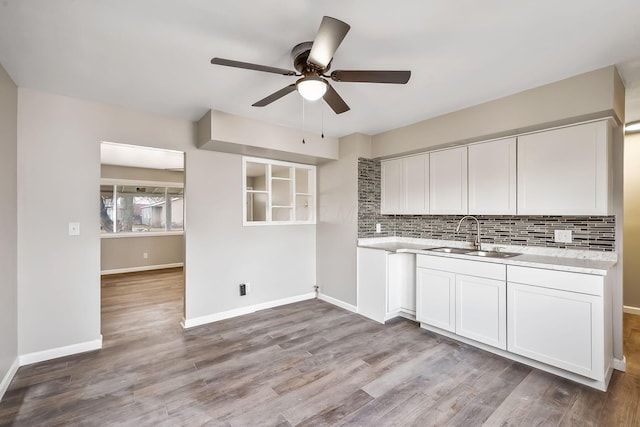 kitchen with hardwood / wood-style flooring, white cabinetry, sink, and decorative backsplash