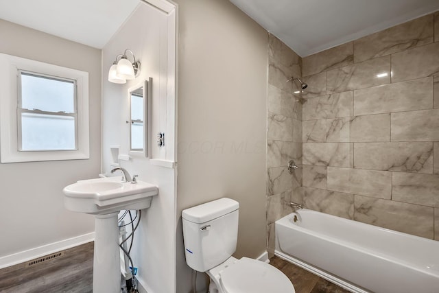 full bathroom with hardwood / wood-style floors, tiled shower / bath combo, sink, and toilet